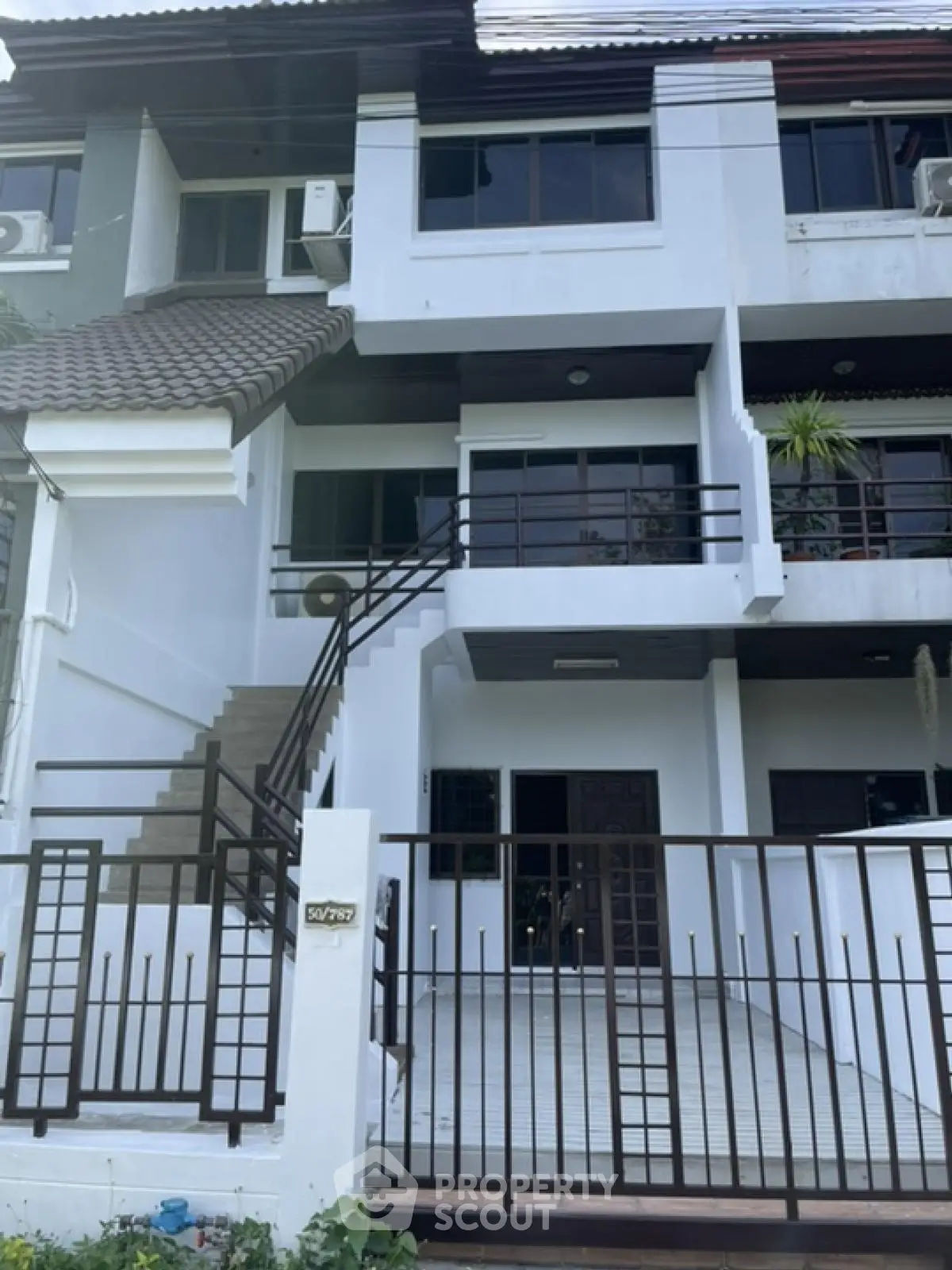 Modern multi-story townhouse with gated entrance and balcony