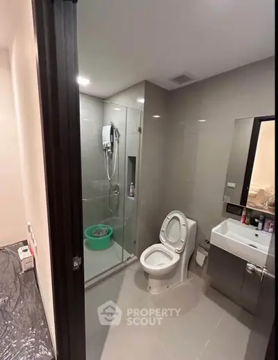 Modern bathroom with glass shower and sleek fixtures in contemporary apartment.