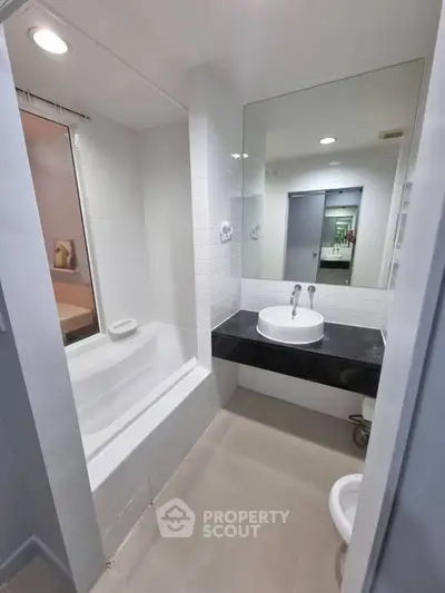 Modern bathroom with sleek design featuring a bathtub and stylish sink area.