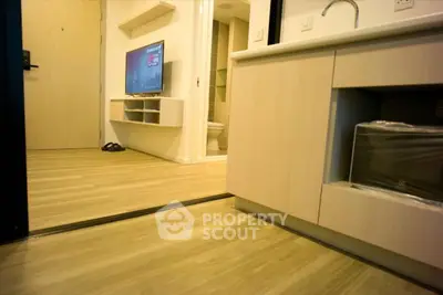 Modern apartment interior with sleek kitchen and cozy living area featuring a wall-mounted TV.