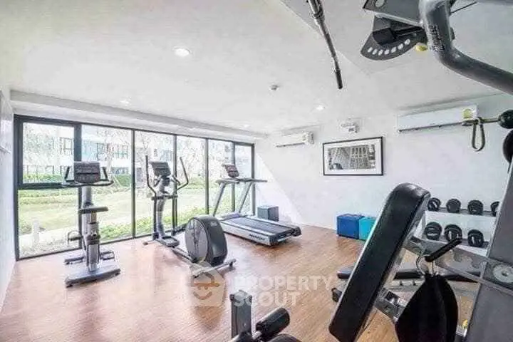 Modern gym with large windows and fitness equipment in a residential building.