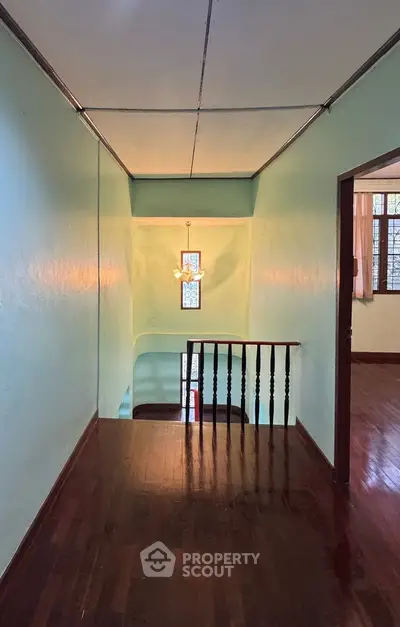 Charming hallway with wooden floors and vintage chandelier in a cozy home.