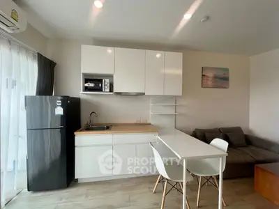 Modern kitchen and living area with sleek white cabinets and cozy seating.