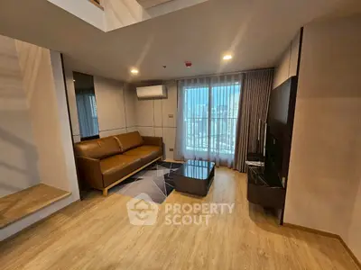 Modern living room with brown leather sofa, wooden flooring, and city view through large window.