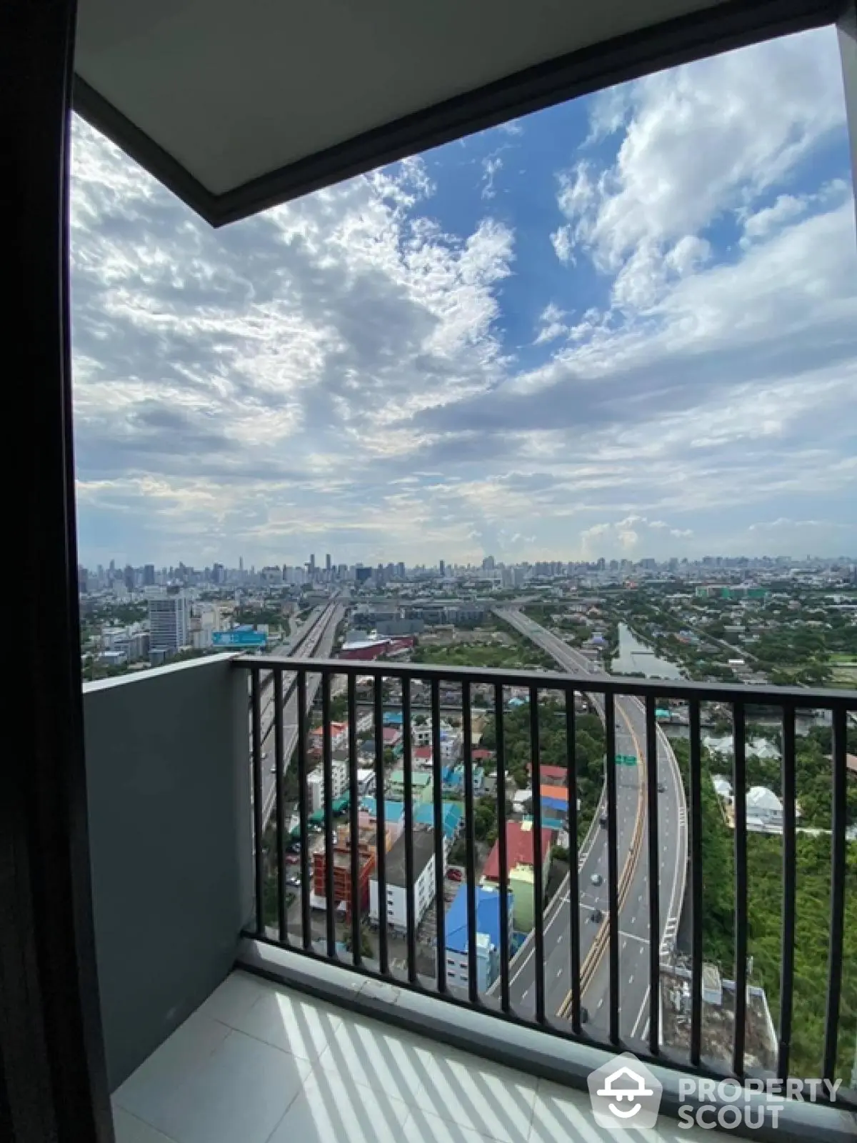 Stunning cityscape view from high-rise balcony with expansive skyline and highway.