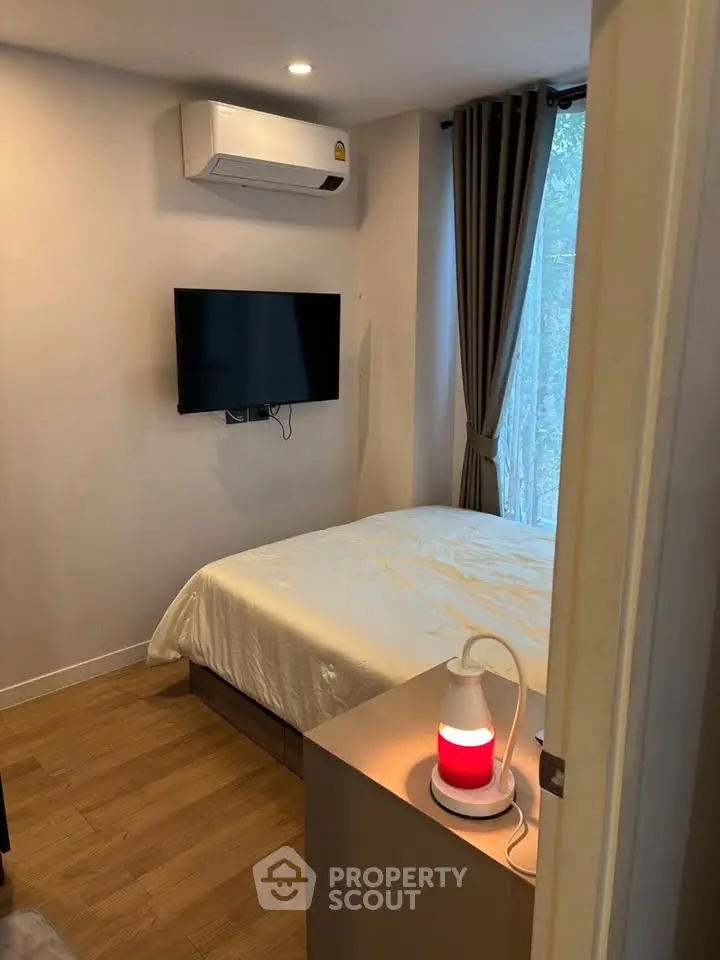 Cozy bedroom with modern decor, featuring a wall-mounted TV and air conditioning.