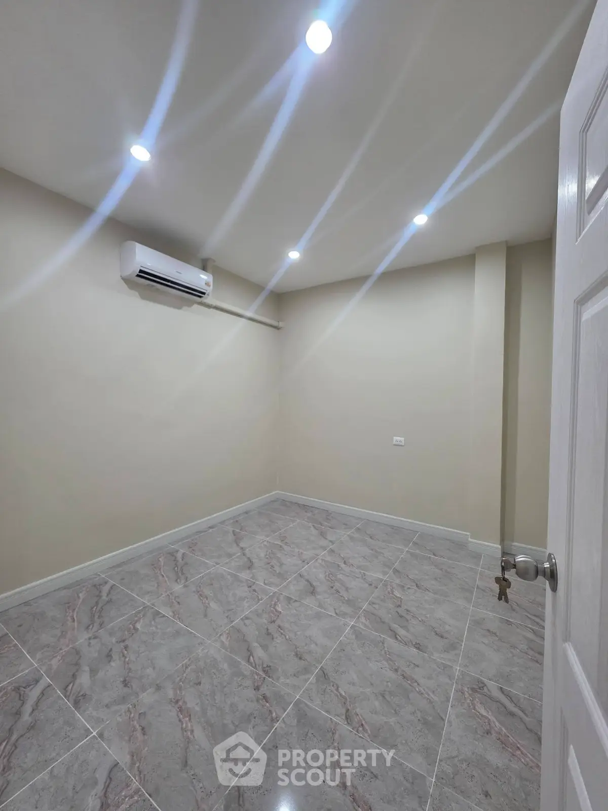 Spacious empty room with modern tile flooring and air conditioning, perfect for customization.