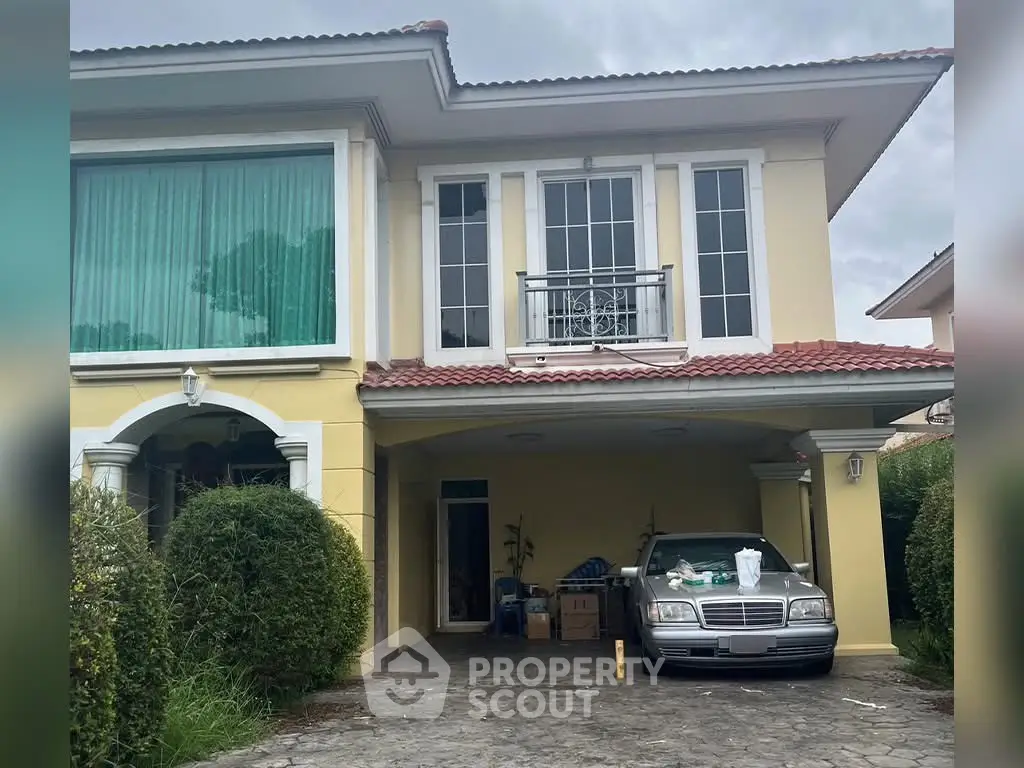 Charming two-story house with a spacious driveway and lush greenery, perfect for family living.