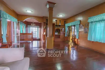 Spacious living room with wooden floors and large windows in a cozy home.