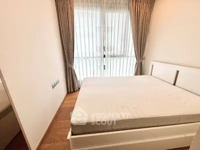 Cozy bedroom with large window and elegant curtains, featuring a comfortable bed and wooden flooring.