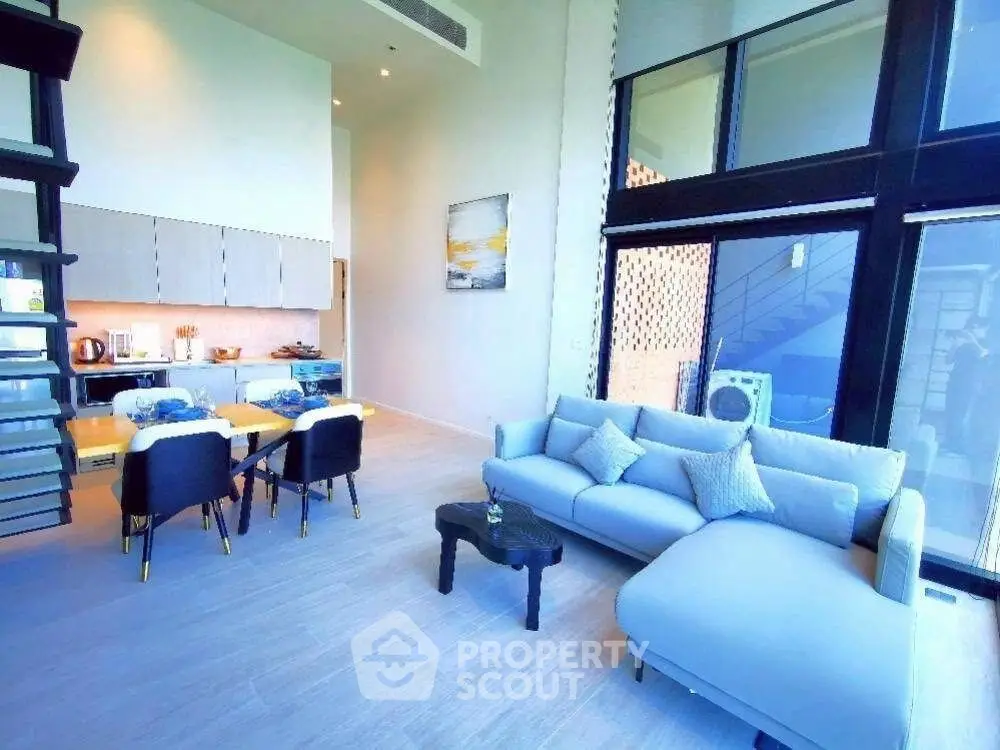 Modern living room with high ceilings, large windows, and stylish furniture in a luxury apartment.