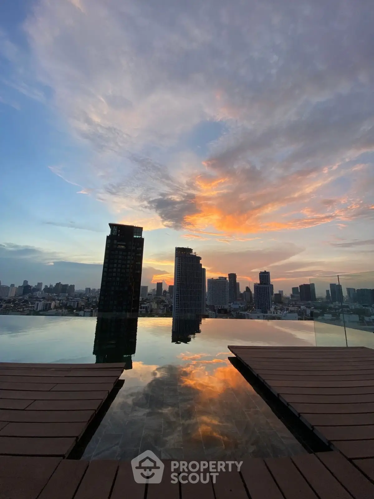 Stunning rooftop pool with breathtaking city skyline view at sunset.