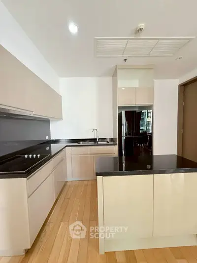 Modern kitchen with sleek cabinetry and black countertops in a stylish apartment.