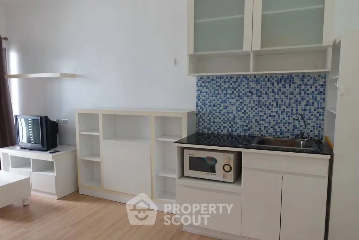 Modern compact kitchen with mosaic backsplash and integrated appliances.