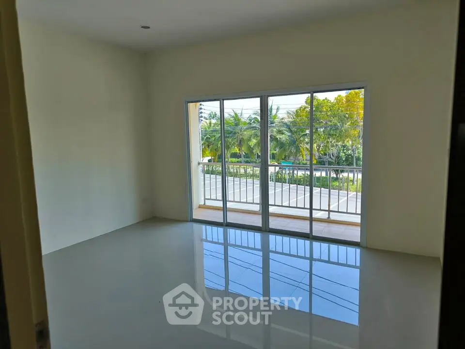 Spacious room with large windows and balcony offering serene views of lush greenery.