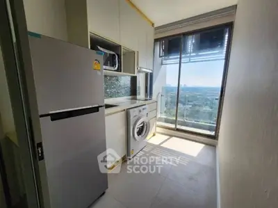 Modern kitchen with city view, featuring fridge and washing machine.