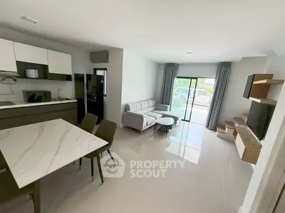 Modern open-plan living room with sleek kitchen and stylish furniture, featuring large windows for natural light.