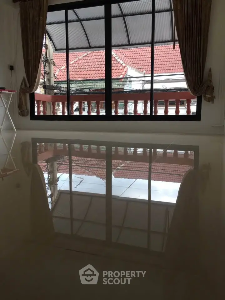 Spacious room with glossy floor and large window overlooking red-tiled rooftops.
