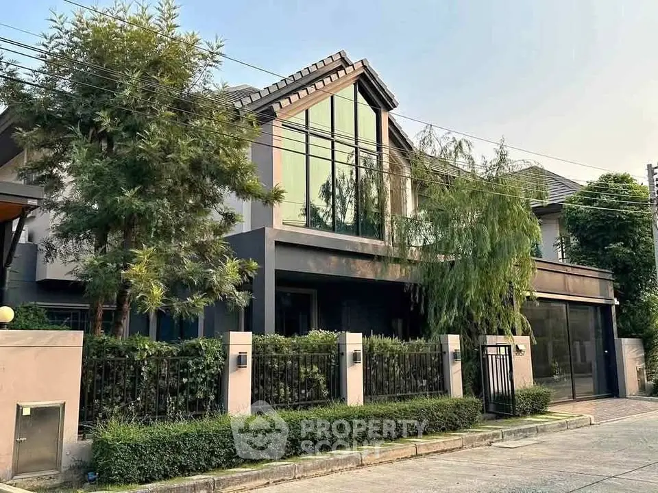 Modern two-story house with large windows and lush greenery