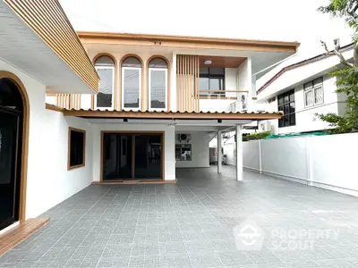 Modern two-story house with spacious tiled driveway and stylish architectural design.