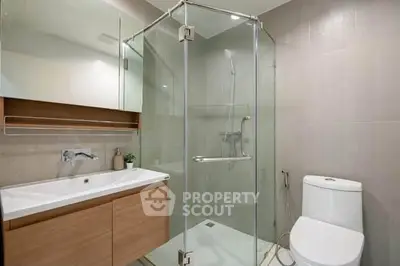 Modern bathroom with glass shower and sleek vanity in contemporary apartment.