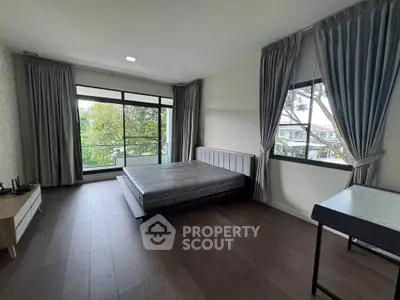 Spacious bedroom with large windows and balcony access, featuring elegant curtains and modern flooring.