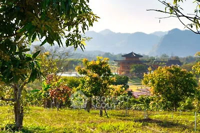 Scenic view of lush garden with mountains and unique architecture in the background.
