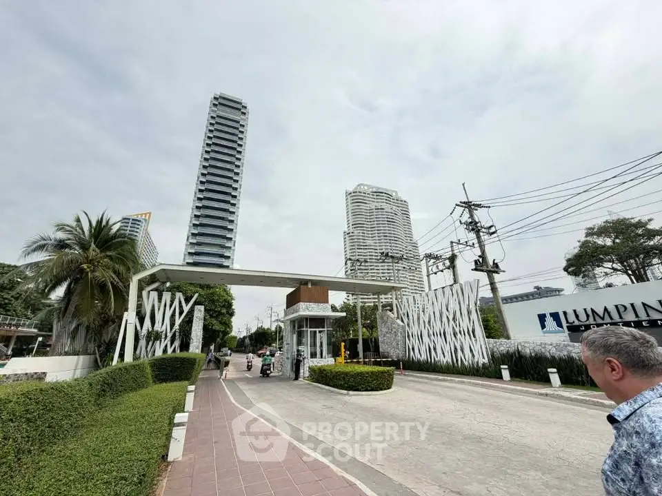 Modern condominium entrance with tall buildings and lush greenery