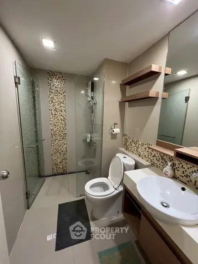 Modern bathroom with glass shower, stylish sink, and elegant tile accents.