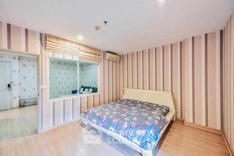 Spacious bedroom with stylish striped wallpaper and cozy bed in modern apartment.