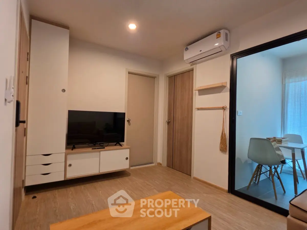 Modern living room with TV, air conditioning, and adjacent dining area in stylish apartment.