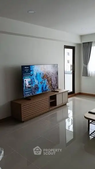 Modern living room with sleek TV setup and balcony access