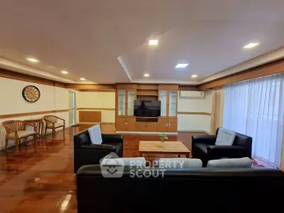 Spacious living room with elegant wooden flooring and modern furniture, perfect for relaxation and entertainment.