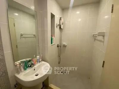 Compact bathroom with modern fixtures and wall-mounted shower in a cozy apartment.