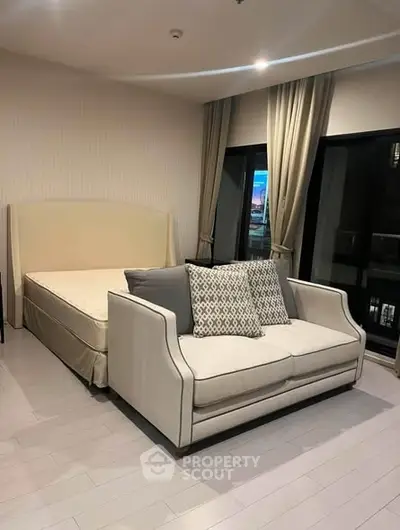 Spacious bedroom with elegant sofa and large windows in modern apartment.