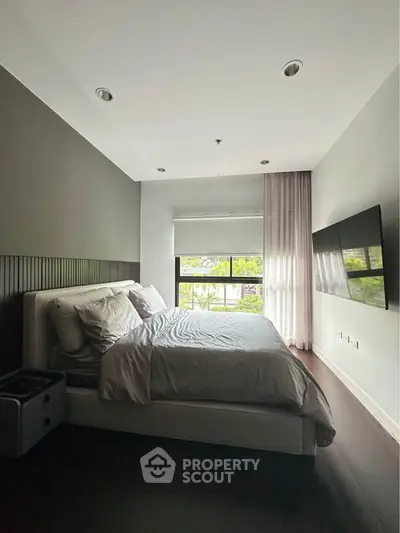 Modern bedroom with large window and sleek decor, perfect for relaxation and comfort.