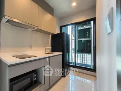 Modern kitchen with sleek appliances and large window offering natural light and city view.