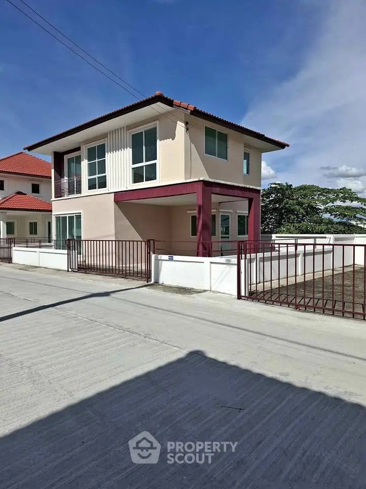 Modern two-story house with red roof and spacious driveway in a serene neighborhood.