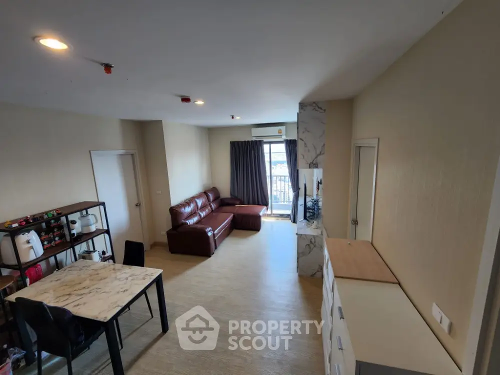 Spacious modern living room with marble table and leather sofa, featuring a balcony view.