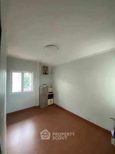 Spacious empty room with wooden flooring and natural light