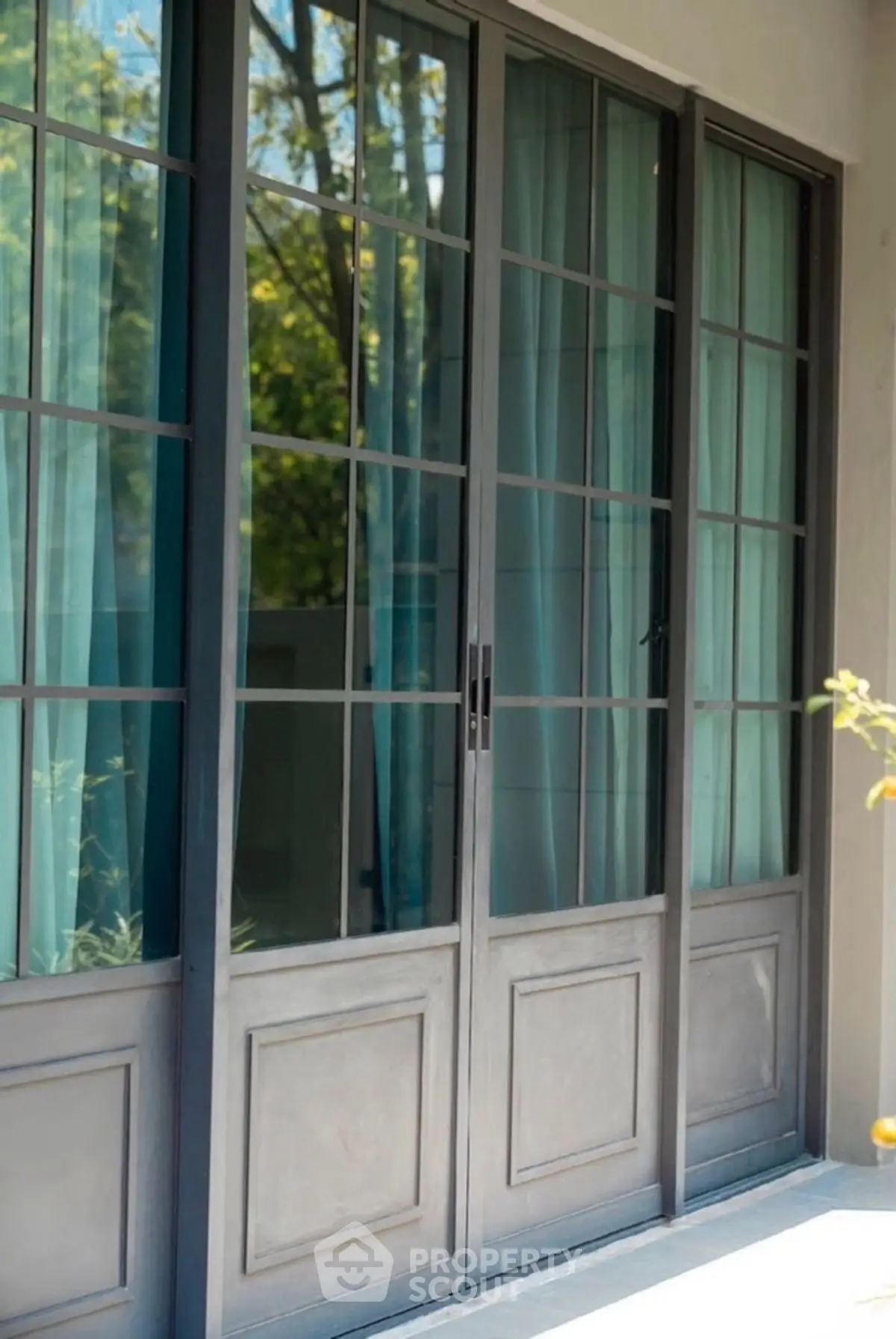 Elegant glass doors with black frames leading to a lush garden view.