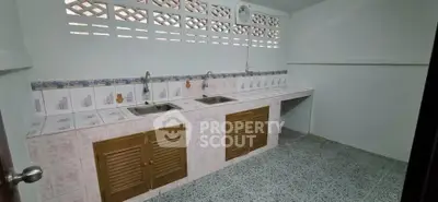 Spacious kitchen with dual sinks and tiled countertops in a modern home.