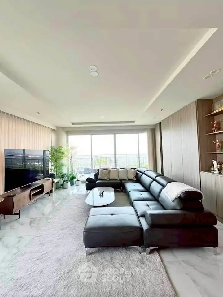 Spacious modern living room with large sectional sofa and floor-to-ceiling windows offering natural light.