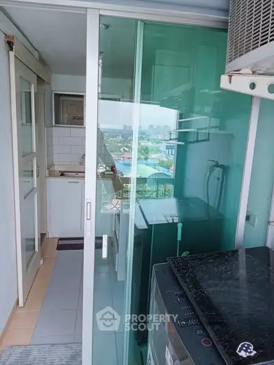 Compact balcony with washing machine and city view, ideal for urban living.