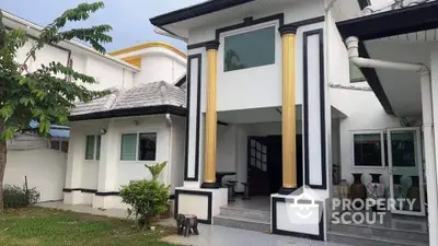 Elegant white house with gold columns and lush garden