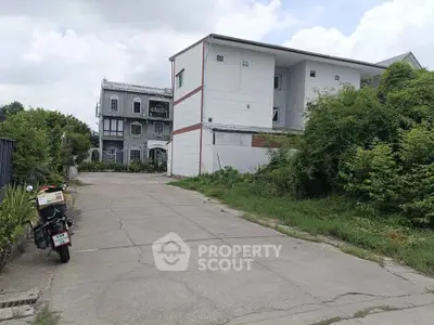 Charming residential buildings with lush greenery and spacious driveway, perfect for serene living.