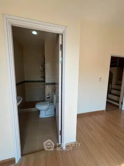 Cozy bathroom with modern fixtures and wooden flooring in a bright apartment.