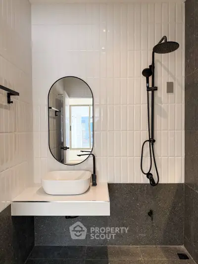 Modern bathroom with sleek black fixtures and stylish oval mirror