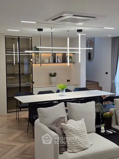 Modern open living and dining area with stylish lighting and cozy seating.