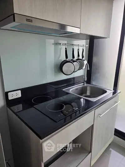Modern compact kitchen with sleek black countertop and induction stove